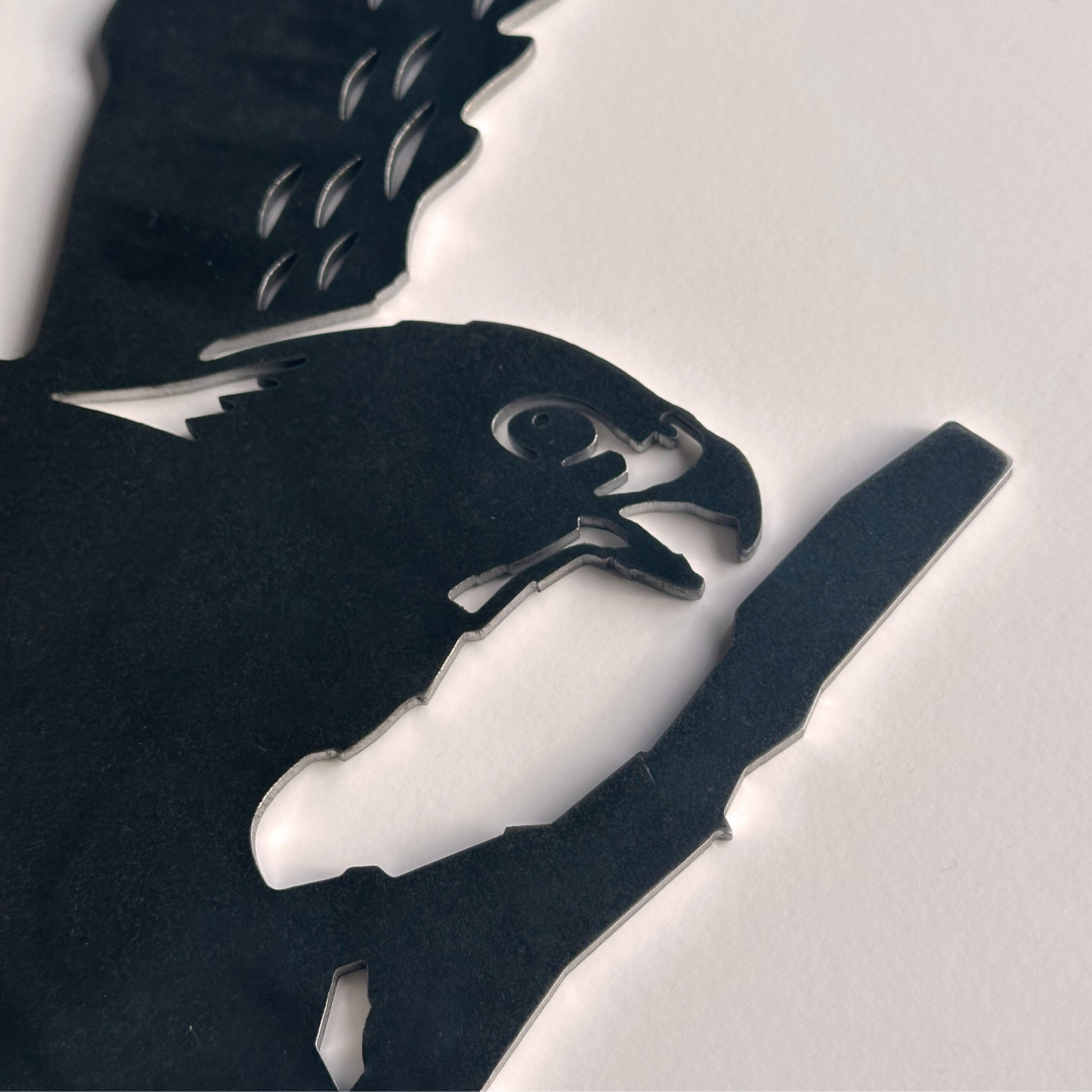 A close-up of Metalbird New Zealand's Kārearea: Wings of Glory silhouette, inspired by the NZ Falcon, Bird of the Year 2025, shows the detailed black metal cutout with outstretched wings on a white surface.