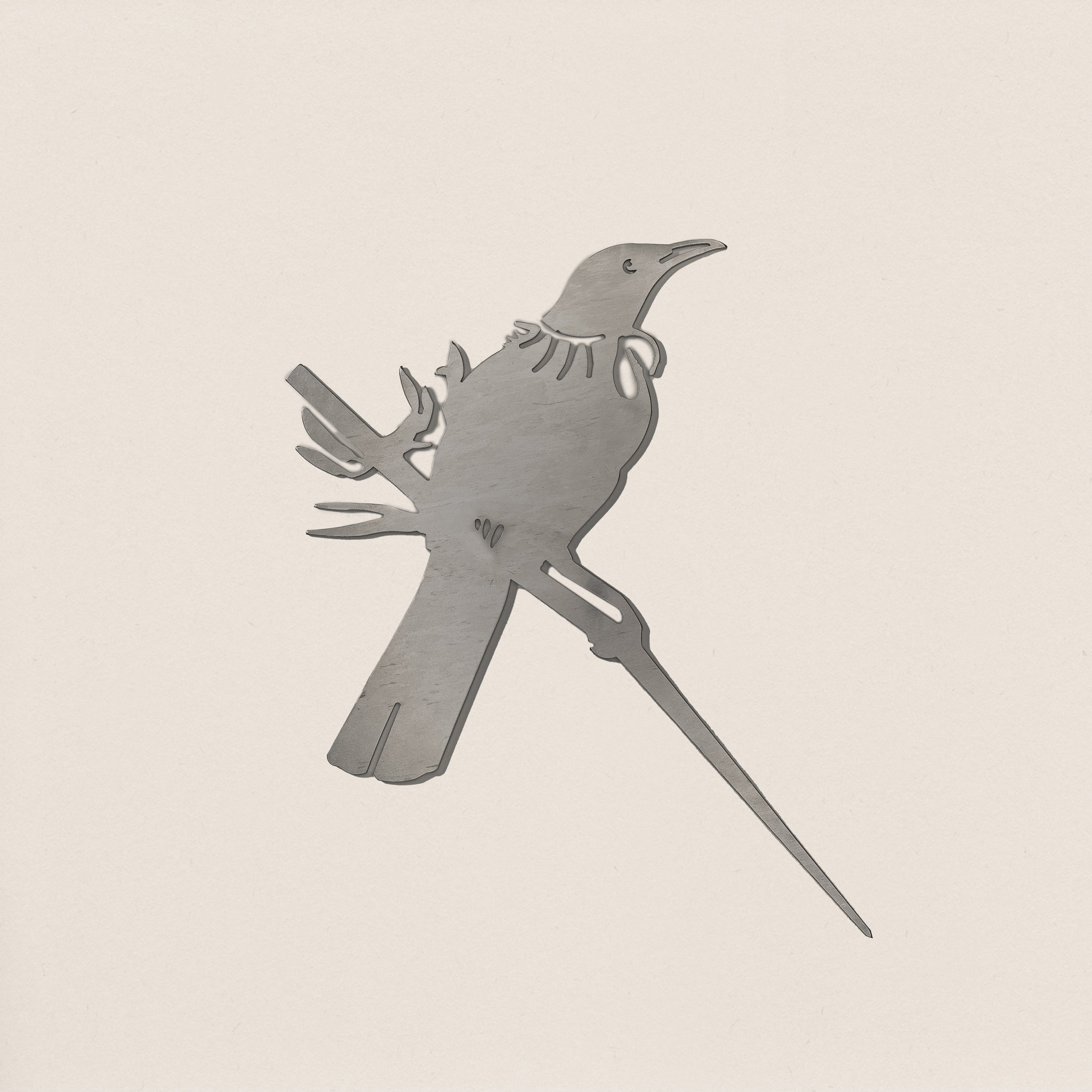 Flat-lay of Tui bird silhouette cut from raw Corten steel, highlighting clean edges and elegant handcrafted detailing