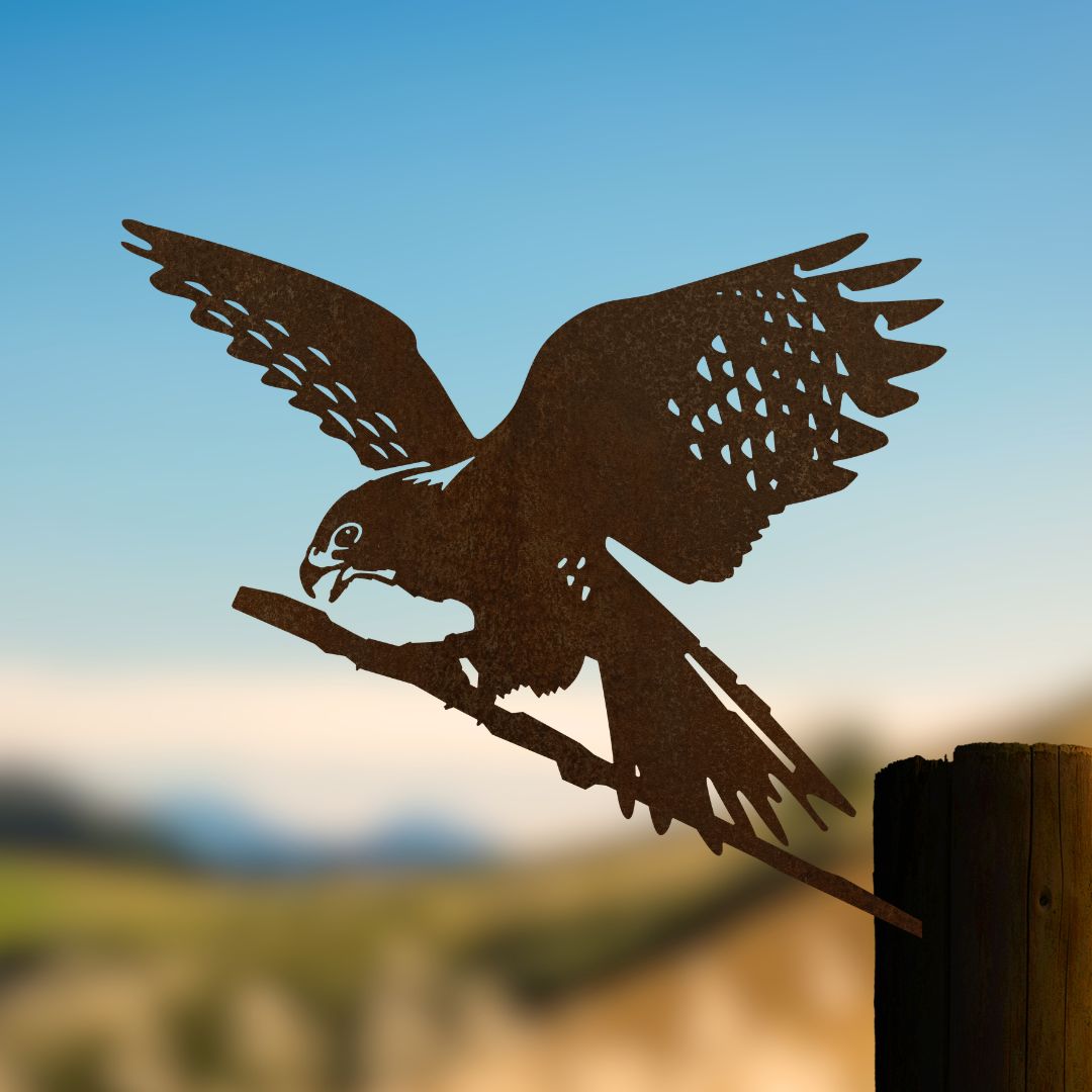 Kārearea falcon steel silhouette with spread wings beside a timber post.