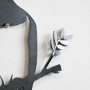Close-up of a metalbird "Metalbird Seconds - PIWAKAWAKA AND BABY - XL" wall art piece, showing a black branch with leaves and birds, highlighting unique imperfections against a textured white wall.