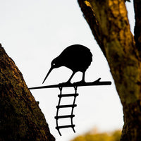 The Metalbird Seconds - KIWI AND LADDER by metalbird features a charming metal kiwi and ladder between trees. This discounted piece has minor imperfections, making it a unique addition to your collection.