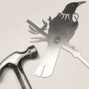 Raw Corten steel Tui bird sculpture beside a hammer, ready for easy installation as outdoor garden art in New Zealand