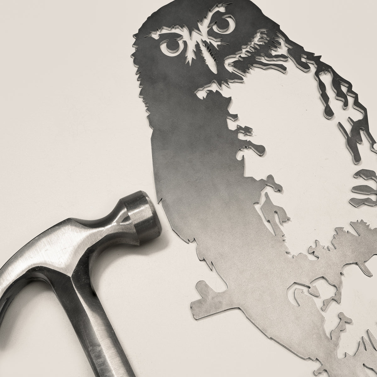 Ruru steel silhouette beside a hammer.