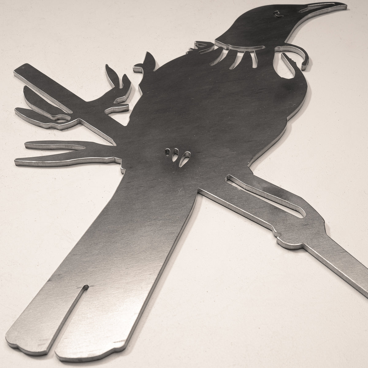 Close-up of the Tūī head, throat tuft and feather cutouts in steel.