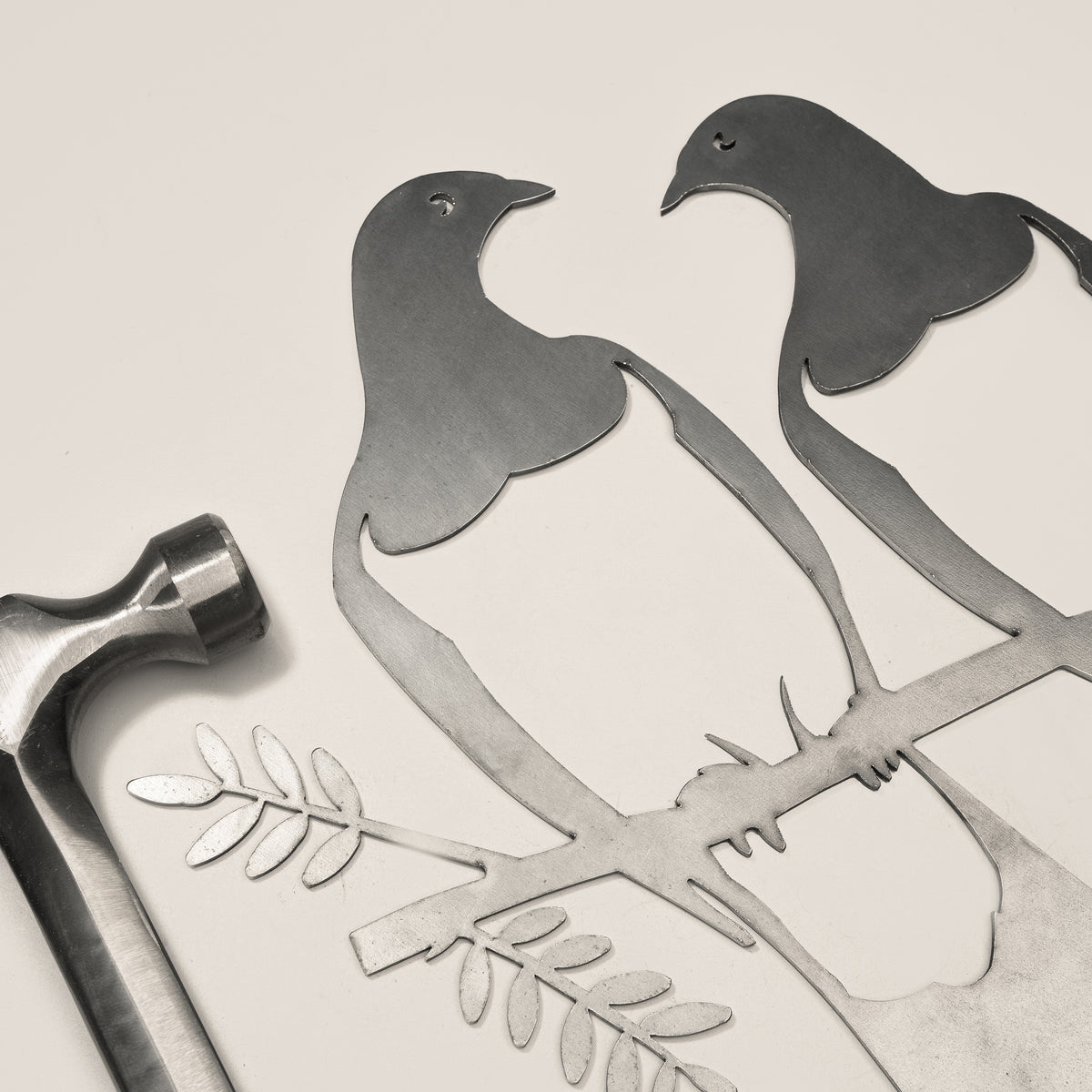 Kererū Pair steel silhouette beside a hammer.
