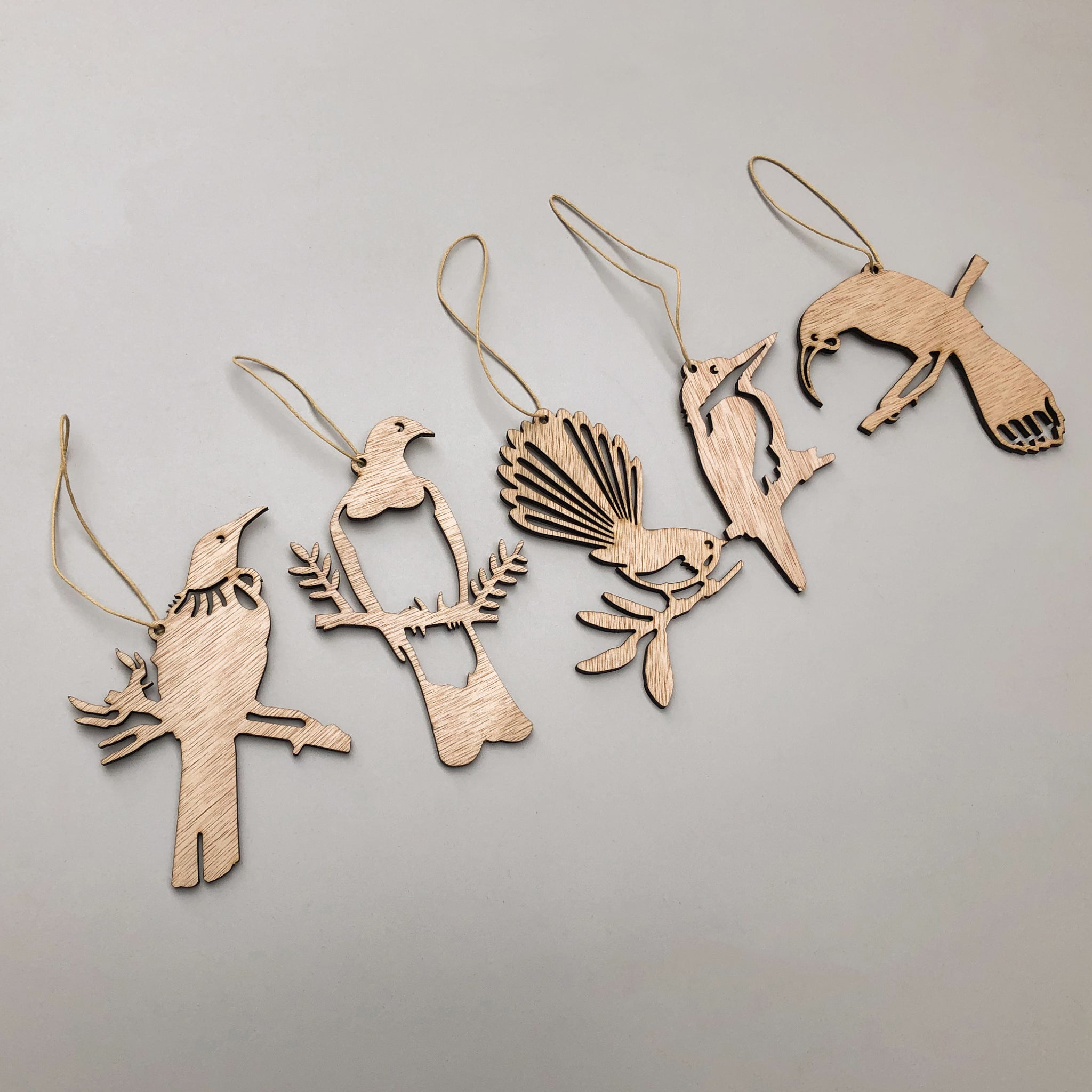 Five festive bird silhouettes—Winged Hangers by Metalbird New Zealand—are arranged in a row on a light gray background. Each sustainably made decoration features a string loop for hanging. Made in Aotearoa.