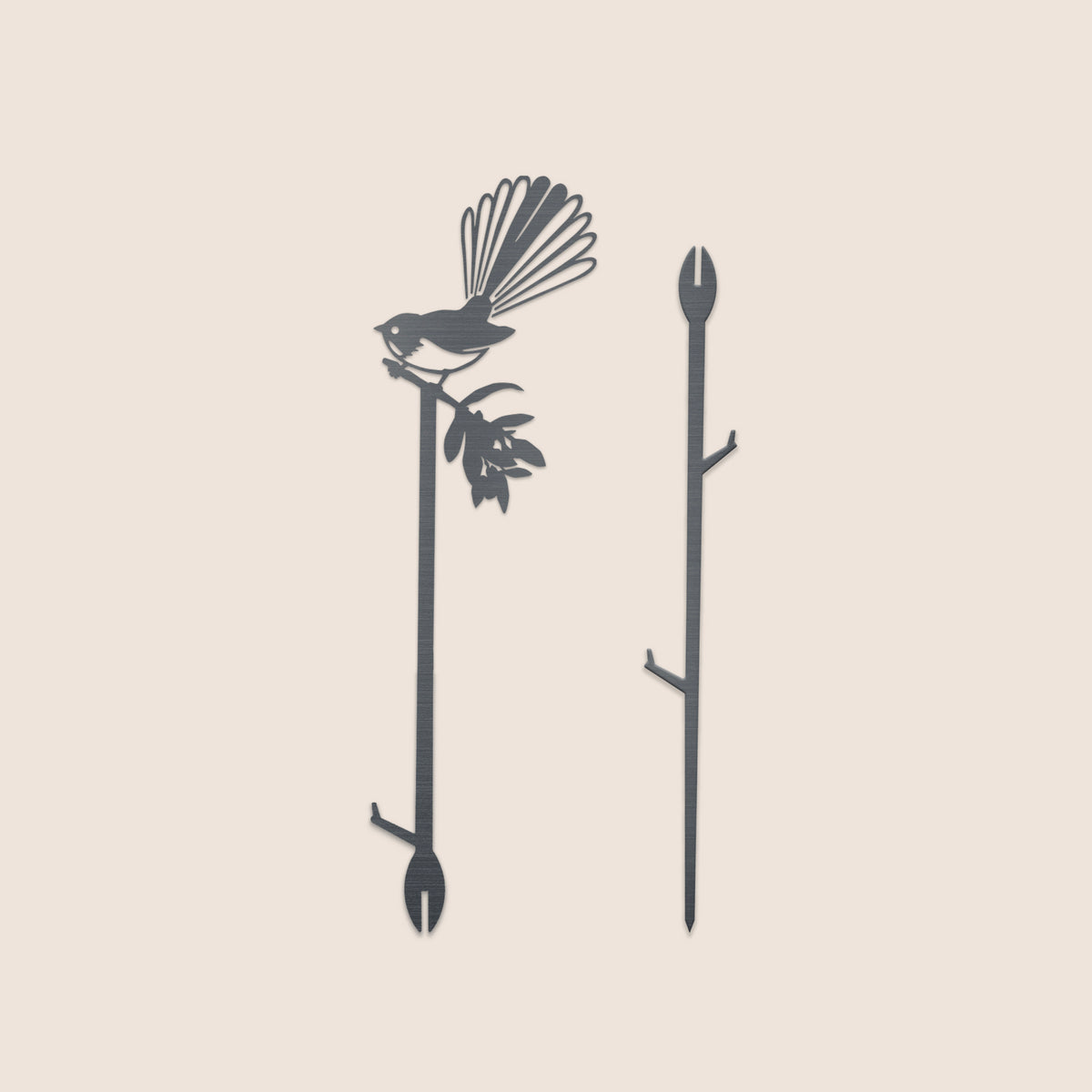 Two Metalbird New Zealand Pīwakawaka Plant Stakes (70cm) are shown: one displays a fanned-tail bird on a leafy branch, the other is plain with two side branches. Both have pointed ends, ideal for unique garden art.