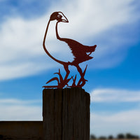 A Pūkeko corten steel bird silhouette by Metalbird New Zealand stands on a wooden post beneath a blue sky with clouds.