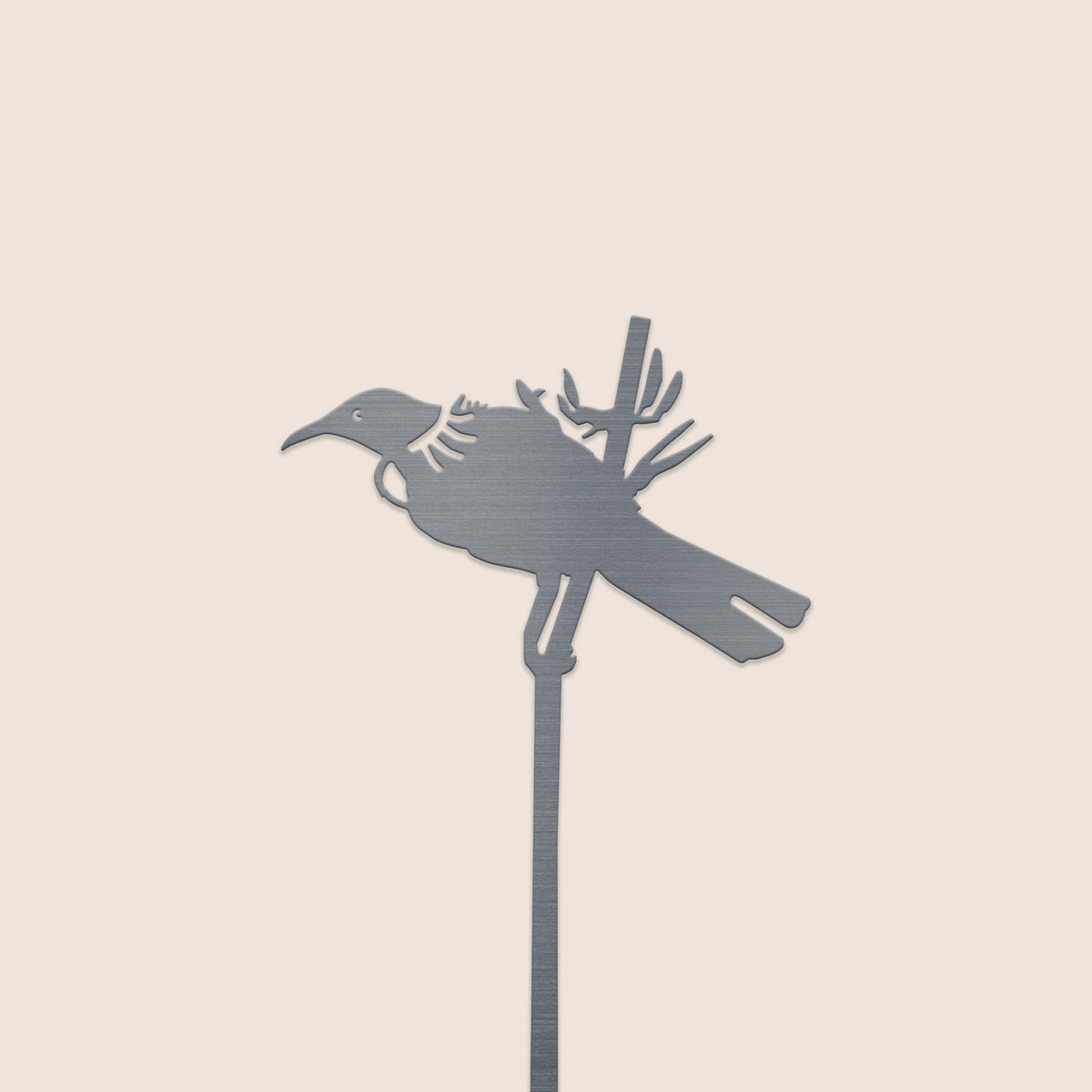 The Tūī Plant Stake - 70cm by Metalbird New Zealand features a corten steel bird perched on a branch atop a slender rod, set against a light beige background—a perfect gift for nature enthusiasts.